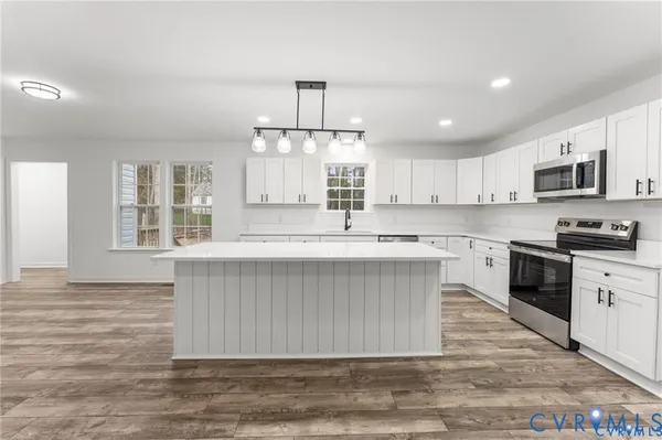 a kitchen with kitchen island granite countertop a stove a sink a refrigerator and a microwave