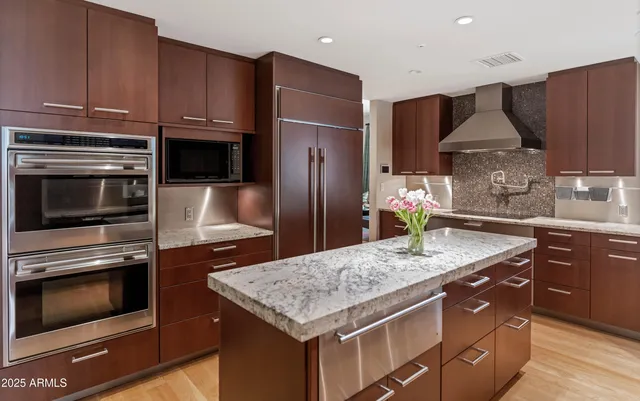 a kitchen with kitchen island granite countertop wooden cabinets stainless steel appliances and a counter space