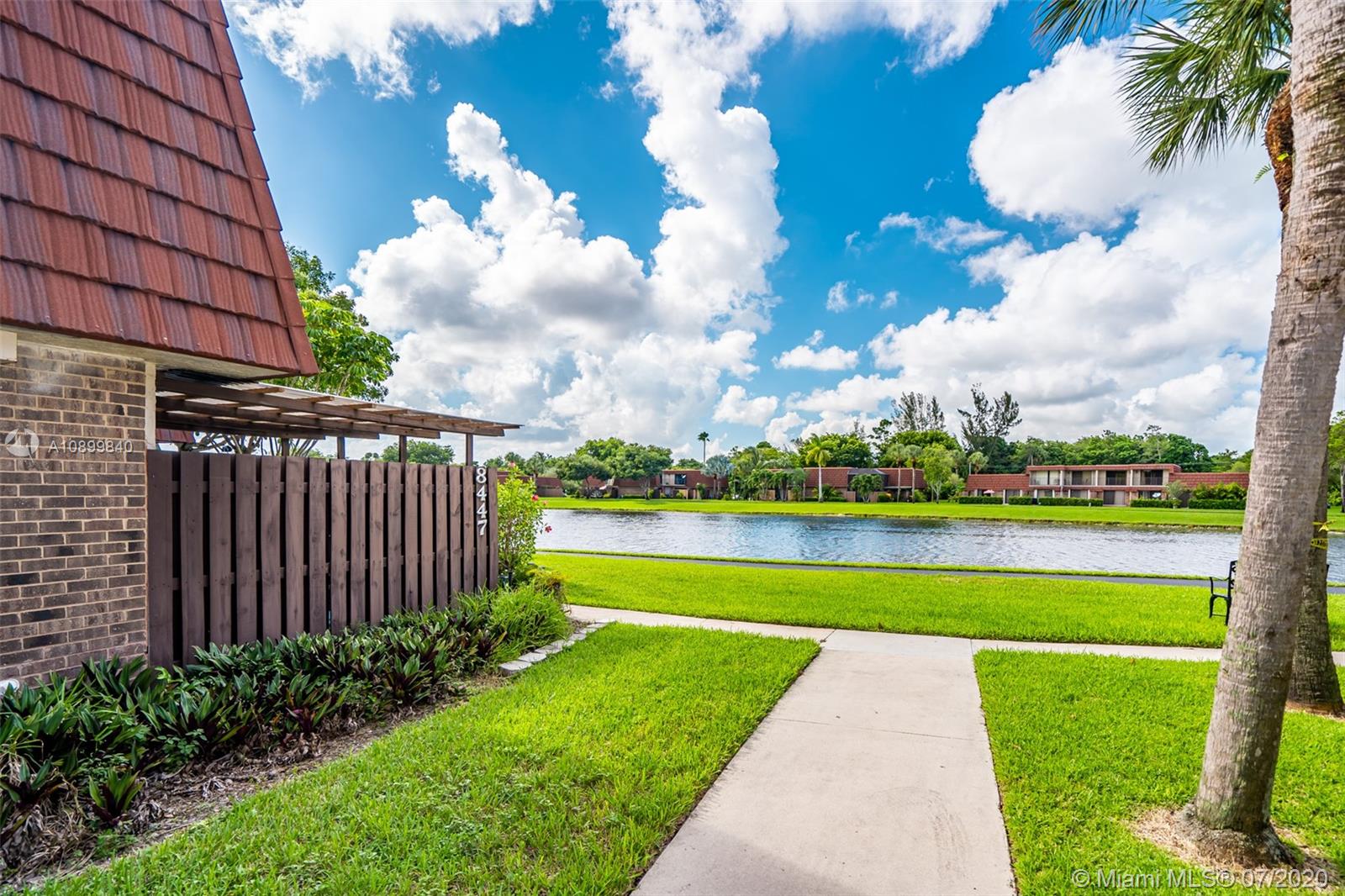 8447 Boca Rio Drive, Unit 8447 Boca Raton, FL 33433 - Photo 1 of 20 a view of a fountain in front of a brick house with a big yard and plants