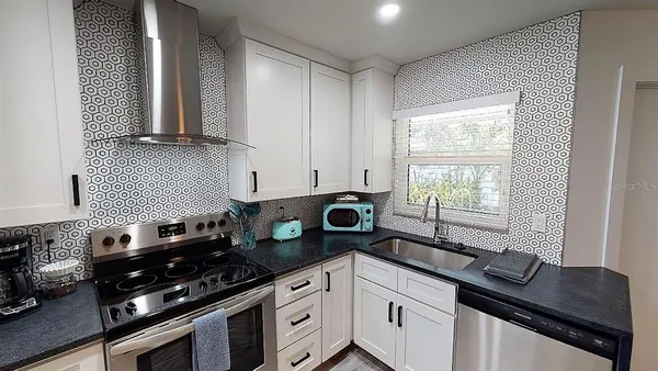 a kitchen with stainless steel appliances granite countertop a refrigerator a stove a sink a counter space and cabinets