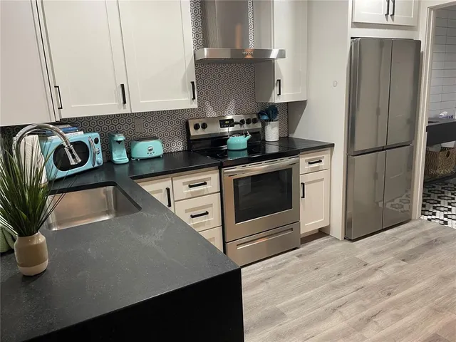 a kitchen with stainless steel appliances granite countertop a sink stove and cabinets