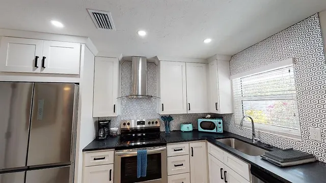 a kitchen with stainless steel appliances granite countertop a stove a sink and a microwave