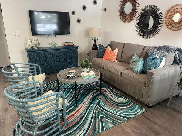a living room with furniture a refrigerator and a dining table with wooden floor