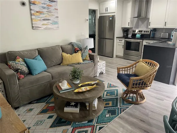 a living room with furniture potted plant and kitchen view