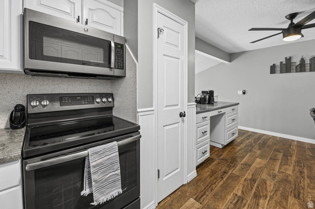 5896 South 3950th Street West Roy, UT 84067 - Photo 8 of 29 Kitchen featuring stainless steel appliances, white cabinetry, dark wood-style floors, built in desk, and a ceiling fan