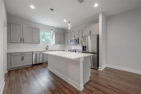a kitchen with a sink dishwasher a refrigerator and a stove with wooden floor