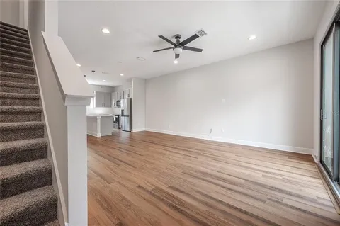 a view of an empty room with wooden floor and a ceiling fan