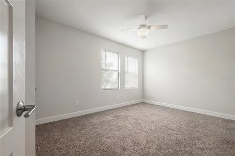 an empty room with windows and ceiling fan