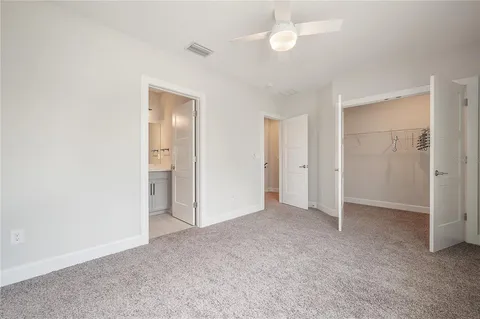 an empty room with closet and a ceiling fan