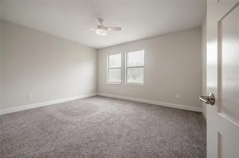 an empty room with windows and chandelier fan