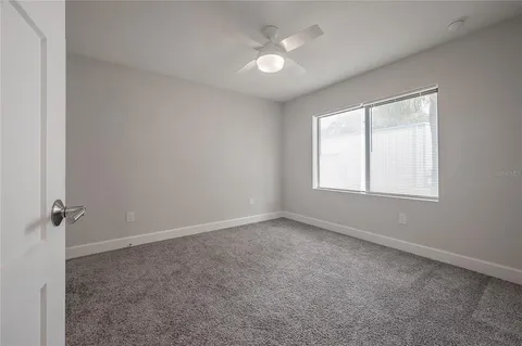 an empty room with a window and a fan