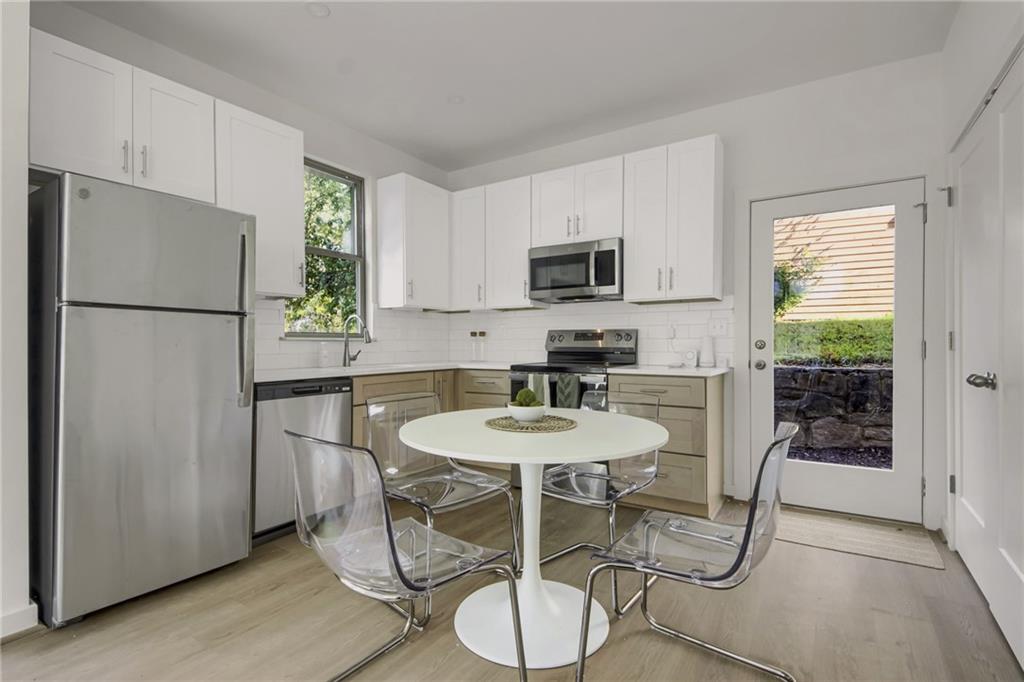 1070 Dill Avenue Southwest, Unit 103 Atlanta, GA 30310 - Photo 4 of 18 a kitchen with stainless steel appliances granite countertop a refrigerator a sink a stove a dining table and chairs