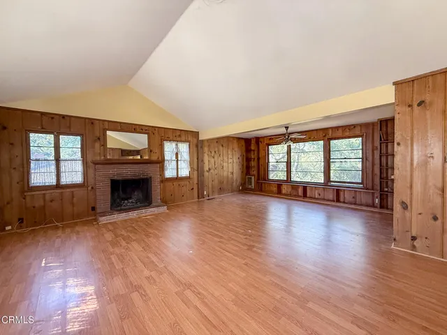 an empty room with large windows and fireplace