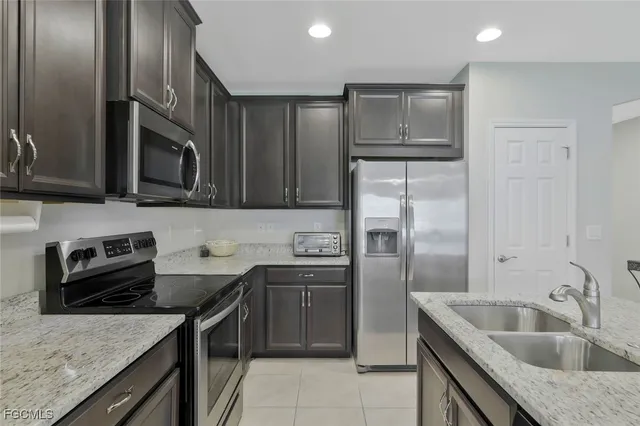 a kitchen with stainless steel appliances granite countertop a sink stove microwave and refrigerator