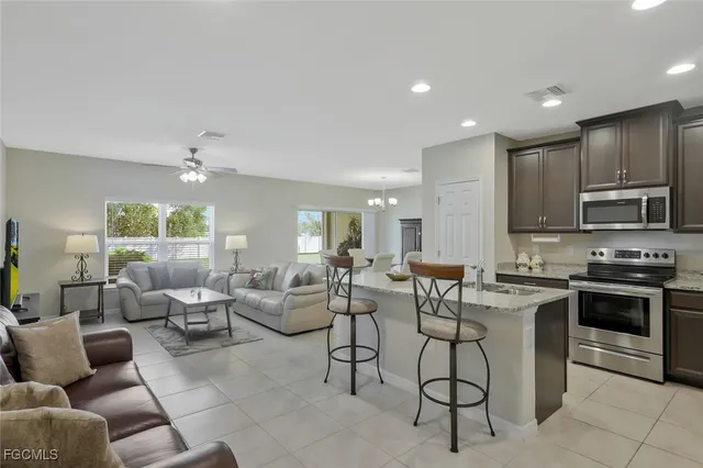 a large kitchen with stainless steel appliances lots of white furniture
