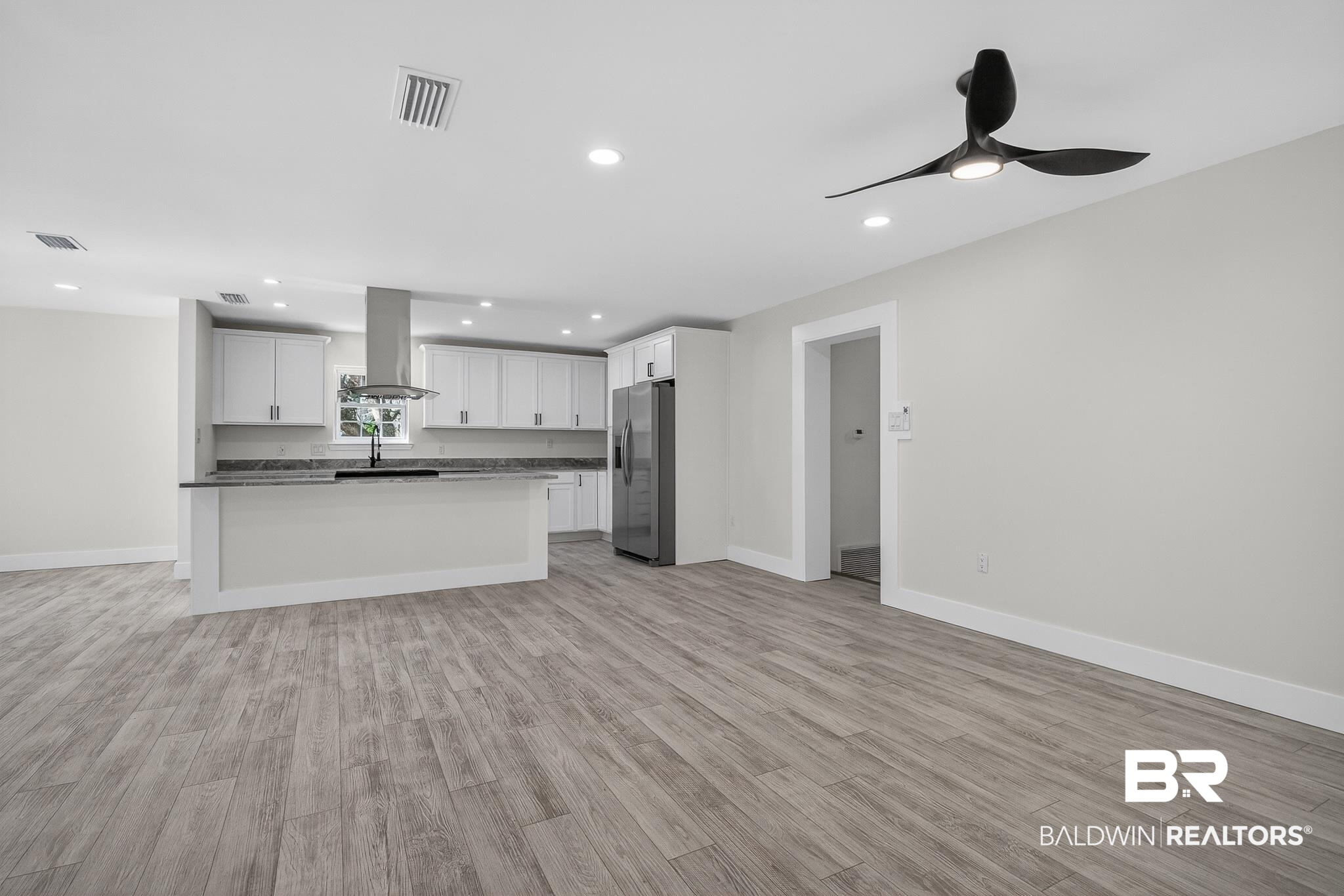 10650 Old Pascagoula Road Theodore, AL 36582 - Photo 77 of 77 Kitchen with stainless steel fridge with ice dispenser, open floor plan, white cabinetry, light wood-style flooring, and island exhaust hood