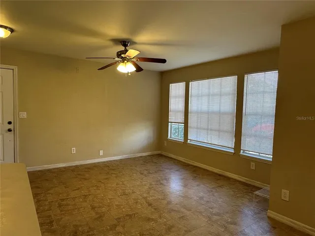 an empty room with windows and fan