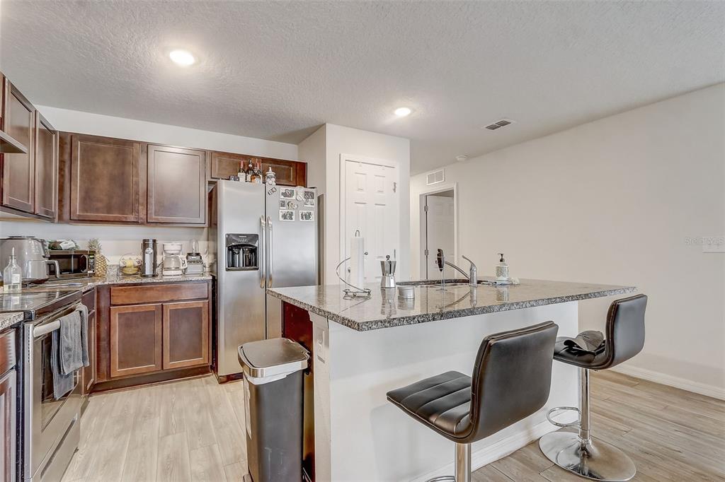 5 Rainbow Lane Palm Coast, FL 32164 - Photo 6 of 16 a kitchen with stainless steel appliances granite countertop a sink a stove a refrigerator cabinets and chairs