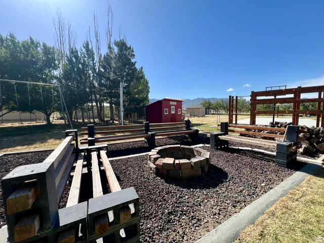 812 East Bates Cyn Road Tooele, UT 84074 - Photo 130 of 144 Outdoor area featuring a stone fire pit, built-in wooden benches on concrete block supports, and a gravel ground cover