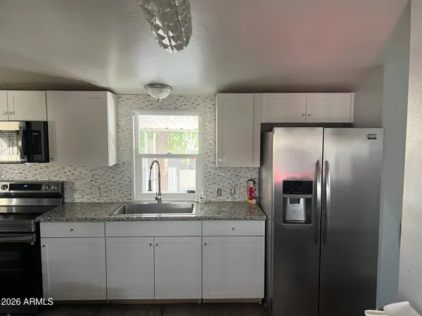 a kitchen with stainless steel appliances granite countertop a refrigerator a stove and a sink