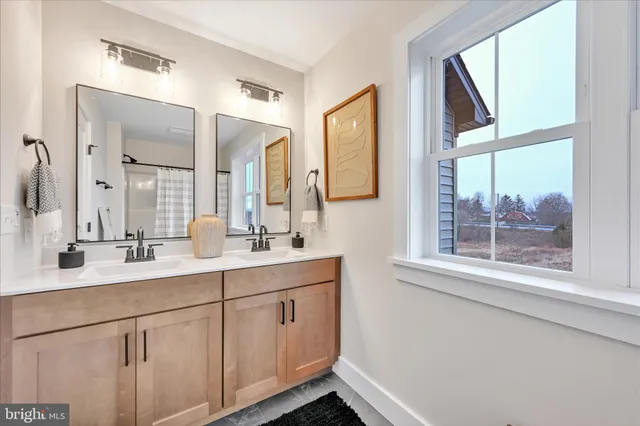 a bathroom with a double vanity sink and mirror with window