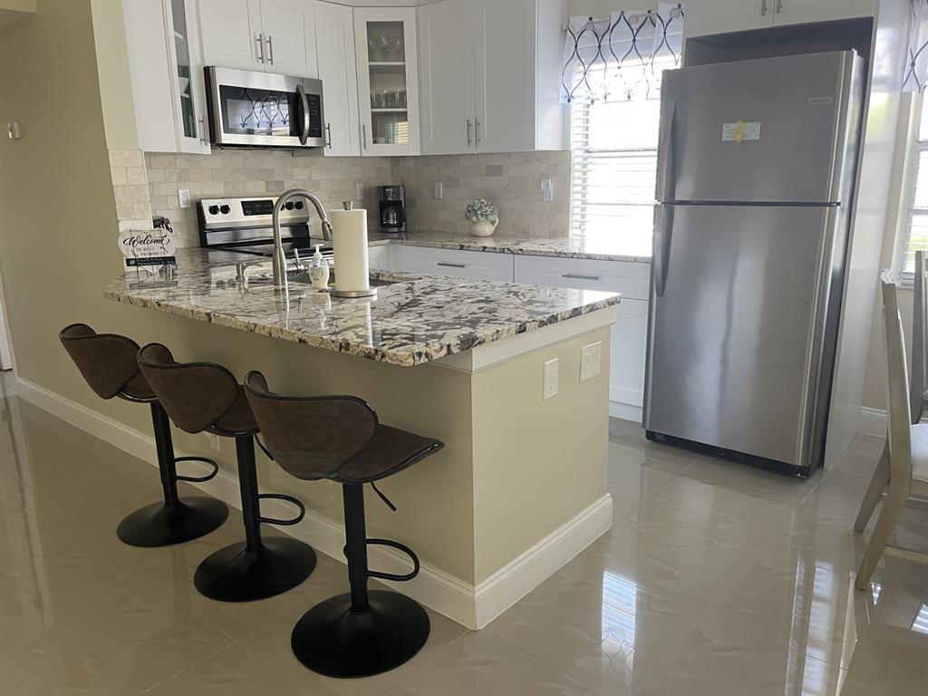 766 Normandy P, Unit 766 Delray Beach, FL 33484 - Photo 1 of 29 a kitchen with stainless steel appliances granite countertop a sink refrigerator and microwave