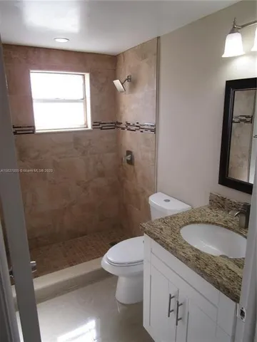 a bathroom with a granite countertop sink a toilet and shower
