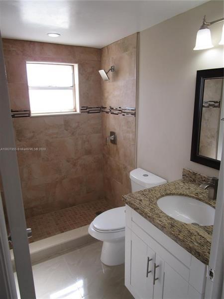 766 Normandy P, Unit 766 Delray Beach, FL 33484 - Photo 11 of 29 a bathroom with a granite countertop sink a toilet and shower