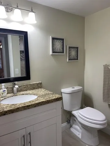a bathroom with a granite countertop toilet sink and mirror