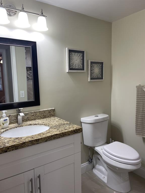 766 Normandy P, Unit 766 Delray Beach, FL 33484 - Photo 12 of 29 a bathroom with a granite countertop toilet sink and mirror