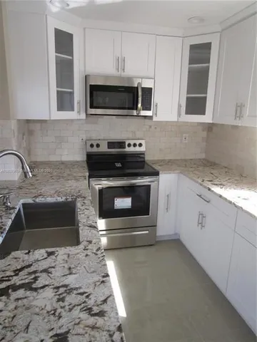 a kitchen with granite countertop a stove top oven microwave and cabinets