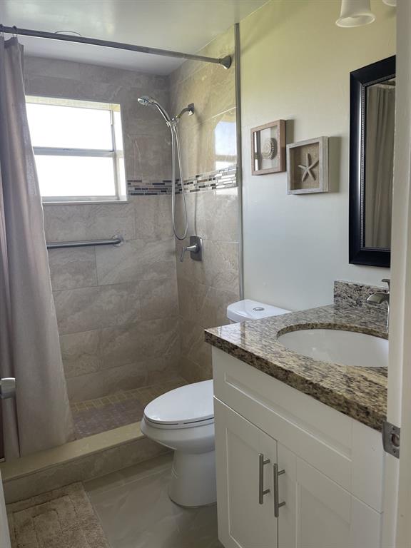 766 Normandy P, Unit 766 Delray Beach, FL 33484 - Photo 9 of 29 a bathroom with a granite countertop sink a toilet and shower
