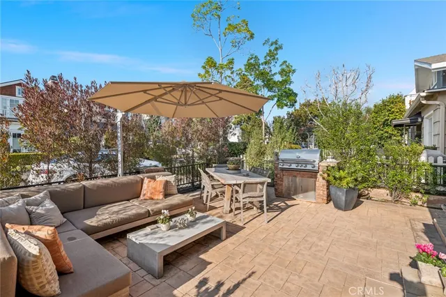 a view of a patio with couches table and chairs under an umbrella with potted plants