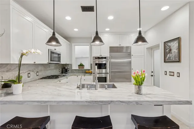 a living room with stainless steel appliances furniture a rug and a view of kitchen