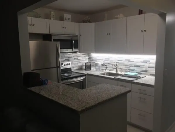 a kitchen with stainless steel appliances granite countertop a sink a stove and a refrigerator