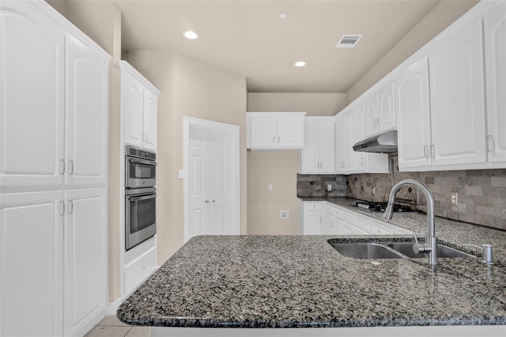 4092 Oberlin Way Addison, TX 75001 - Photo 18 of 40 Kitchen featuring a sink, dark stone countertops, a peninsula, under cabinet range hood, and recessed lighting