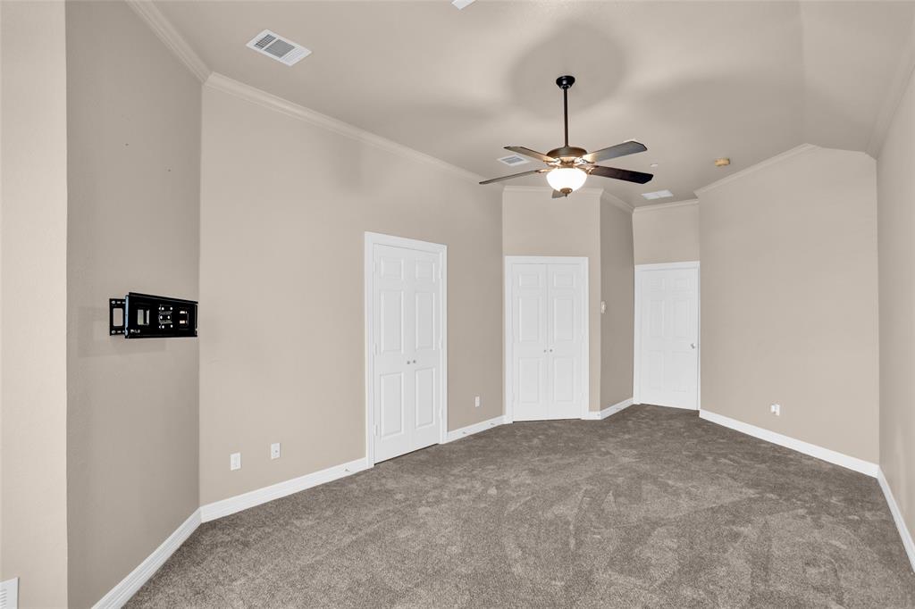 4092 Oberlin Way Addison, TX 75001 - Photo 22 of 40 Unfurnished bedroom featuring dark carpet, crown molding, baseboards, multiple closets, and a ceiling fan