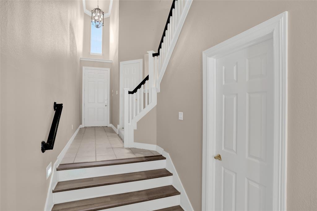 4092 Oberlin Way Addison, TX 75001 - Photo 3 of 40 Stairway with a high ceiling, tile patterned floors, baseboards, and a chandelier