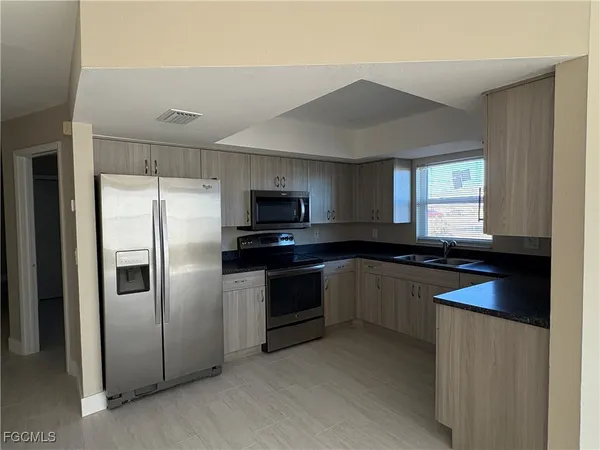 a kitchen with granite countertop a refrigerator stove and sink