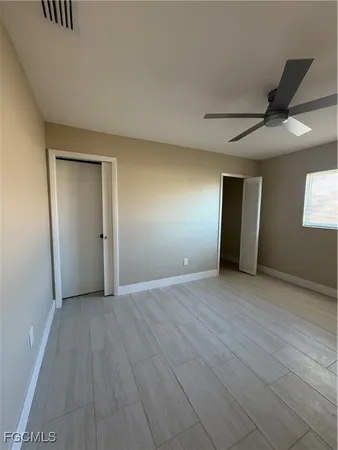 a view of an empty room with window and wooden floor