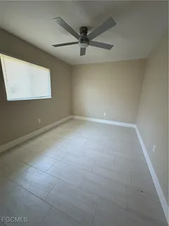 an empty room with windows and ceiling fan