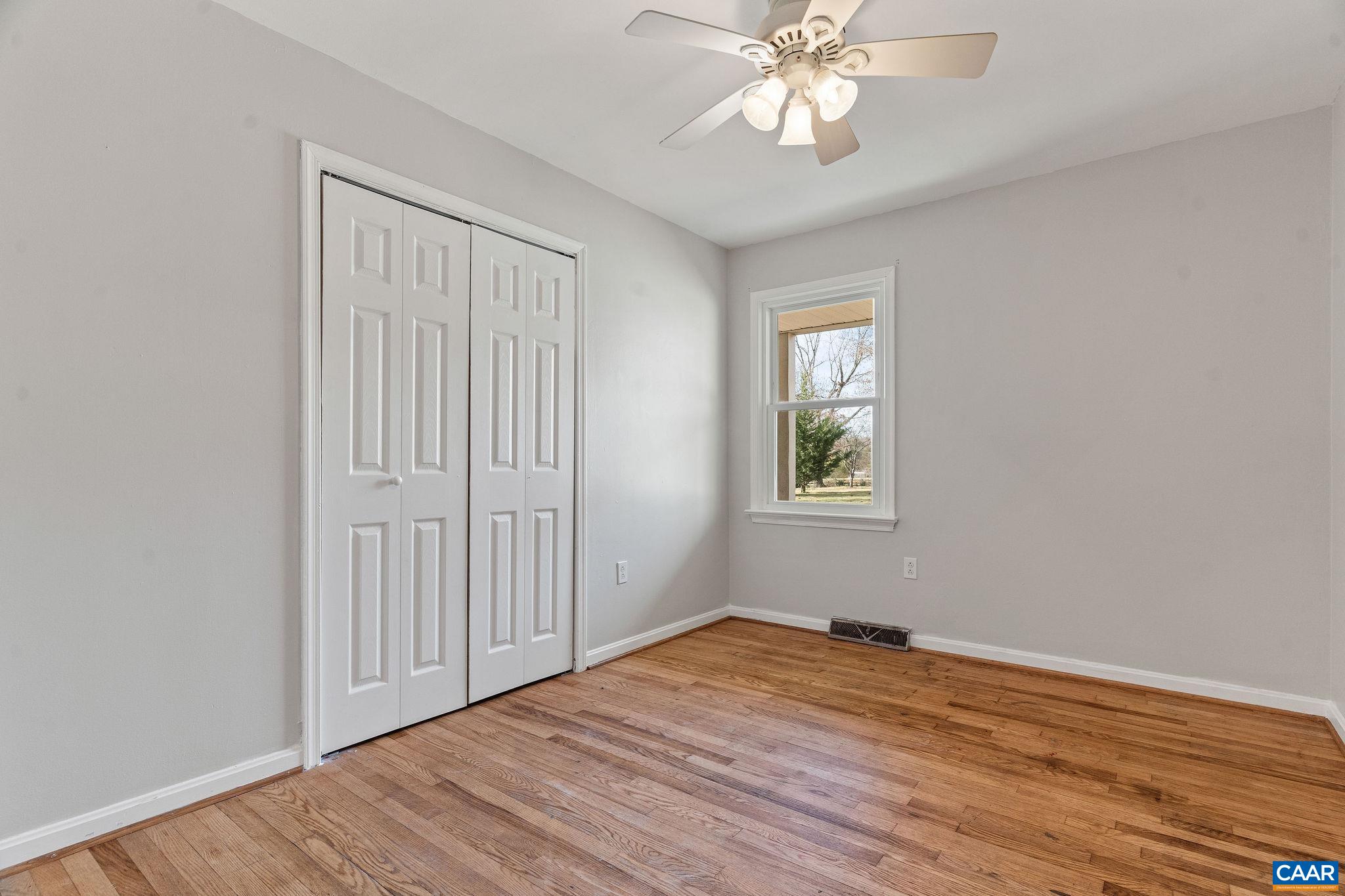 569 Half Mile Branch Road Crozet, VA 22932 - Photo 11 of 35 an empty room with wooden floor chandelier fan and windows