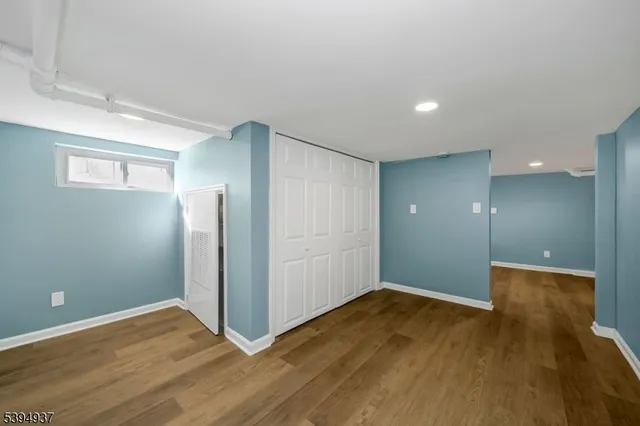 a view of an empty room with wooden floor and closet