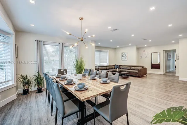 a view of a dining room and livingroom with furniture wooden floor a rug a potted plant and a chandelier