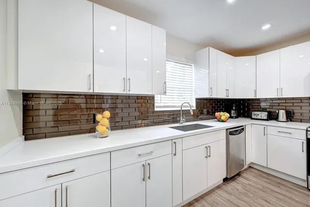 a kitchen with a sink dishwasher a white stove and cabinets with wooden floor