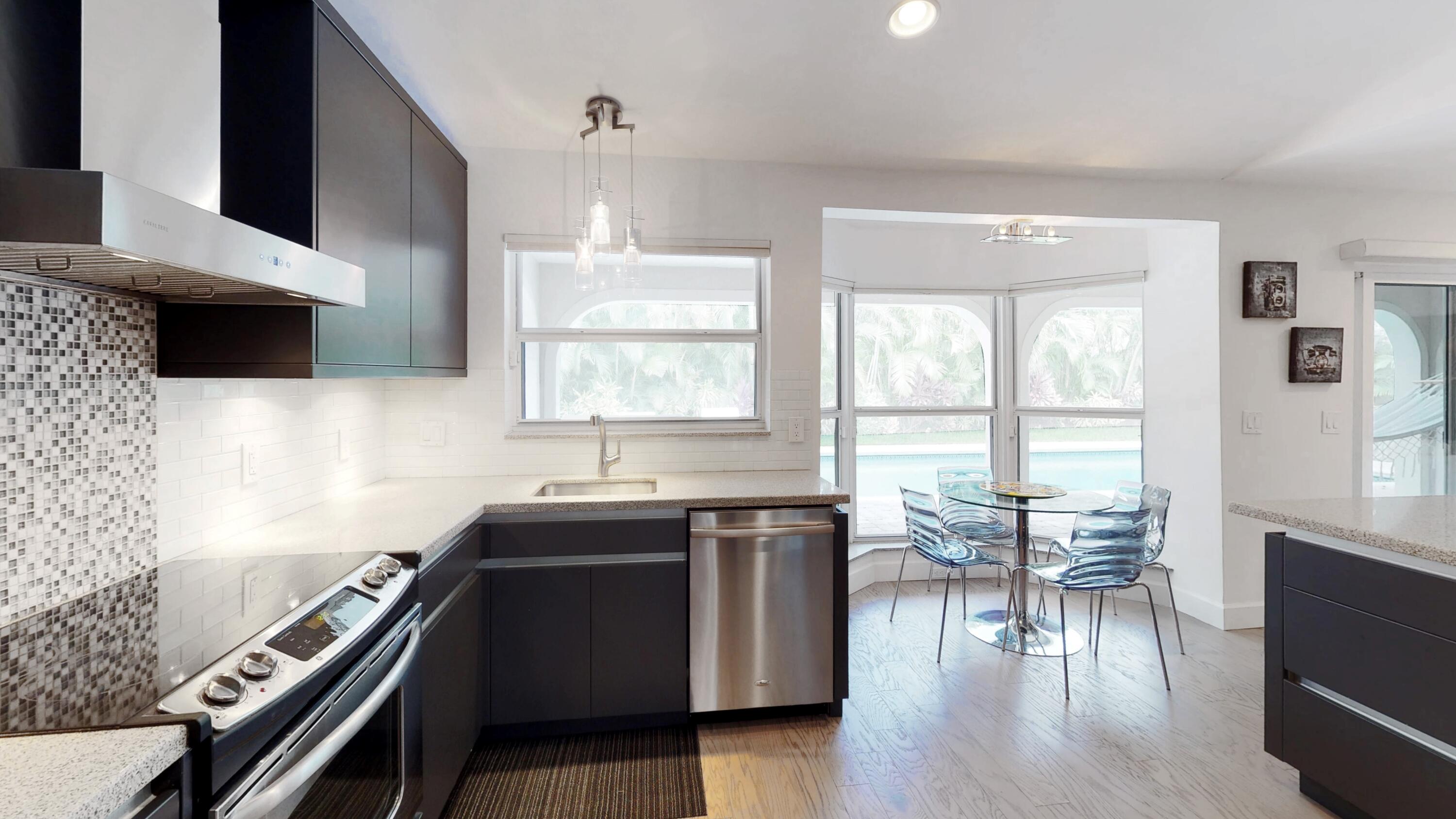 5264 Deerhurst Crescent Circle Boca Raton, FL 33486 - Photo 17 of 62 a kitchen with granite countertop a stove a sink a dining table and chairs