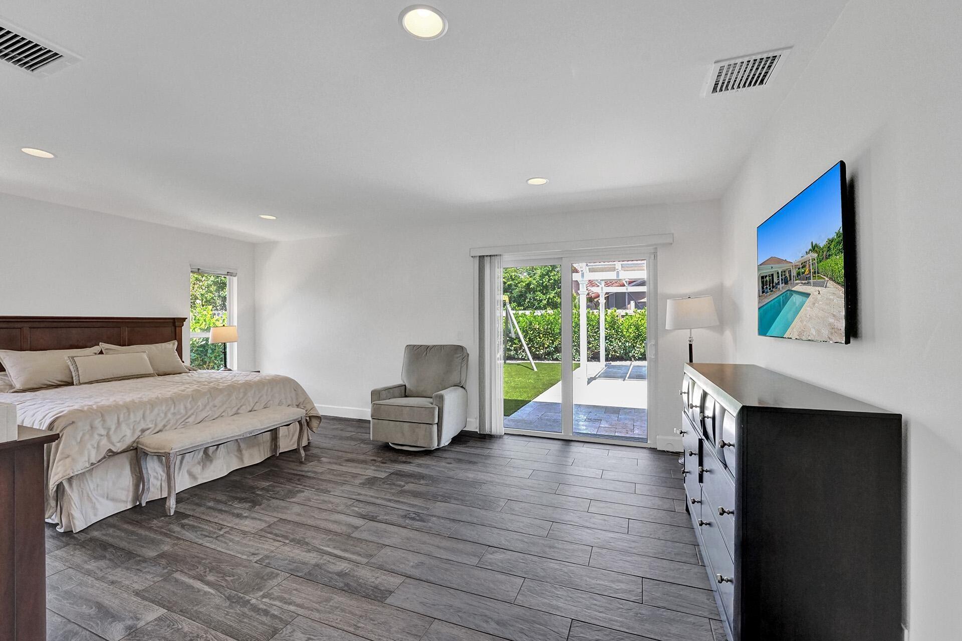 5264 Deerhurst Crescent Circle Boca Raton, FL 33486 - Photo 26 of 62 a spacious bedroom with a large bed a table and a painting on the wall