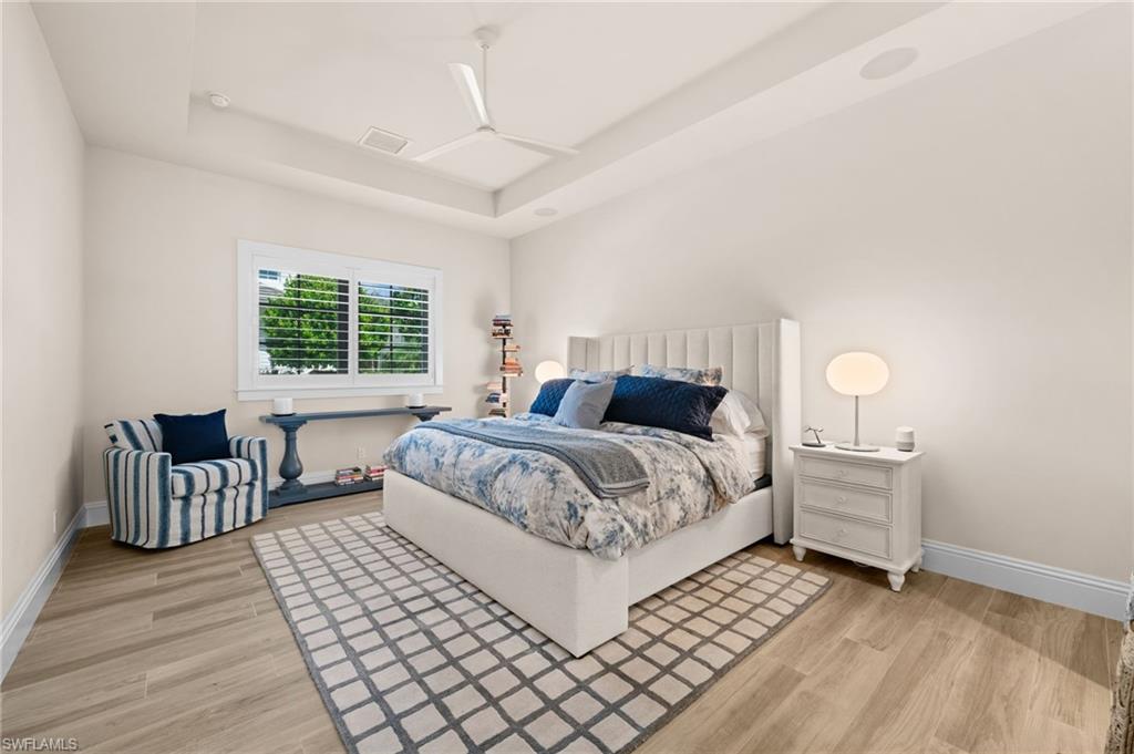 9172 Mercato Lane Naples, FL 34108 - Photo 16 of 29 Bedroom featuring light wood-type flooring, a tray ceiling, and a ceiling fan