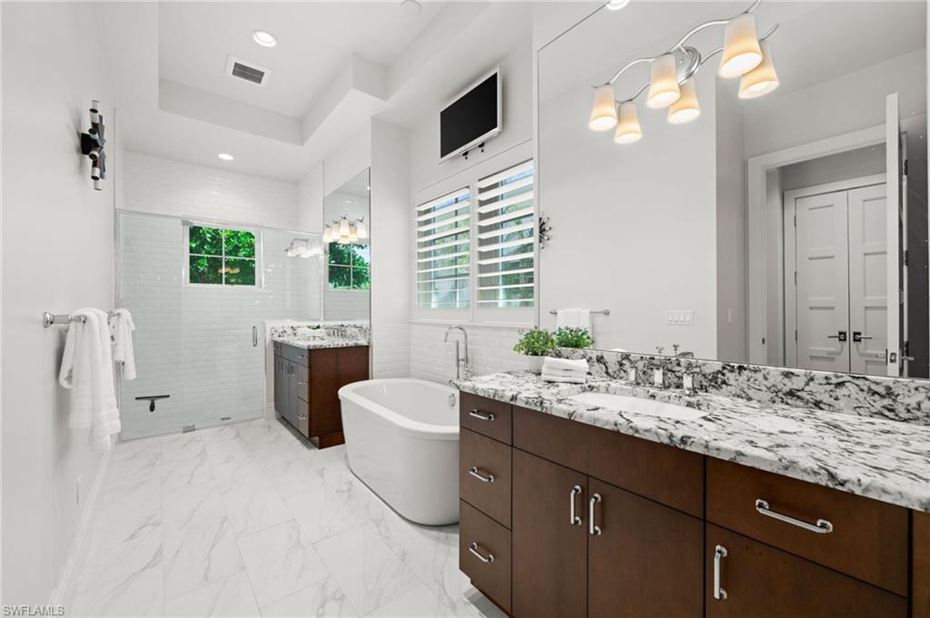 9172 Mercato Lane Naples, FL 34108 - Photo 17 of 29 Full bath featuring two vanities, a stall shower, a soaking tub, recessed lighting, and light marble finish flooring