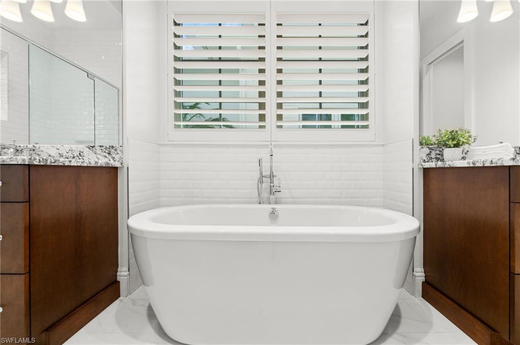 9172 Mercato Lane Naples, FL 34108 - Photo 19 of 29 Bathroom featuring vanity, plenty of natural light, a soaking tub, and tile walls